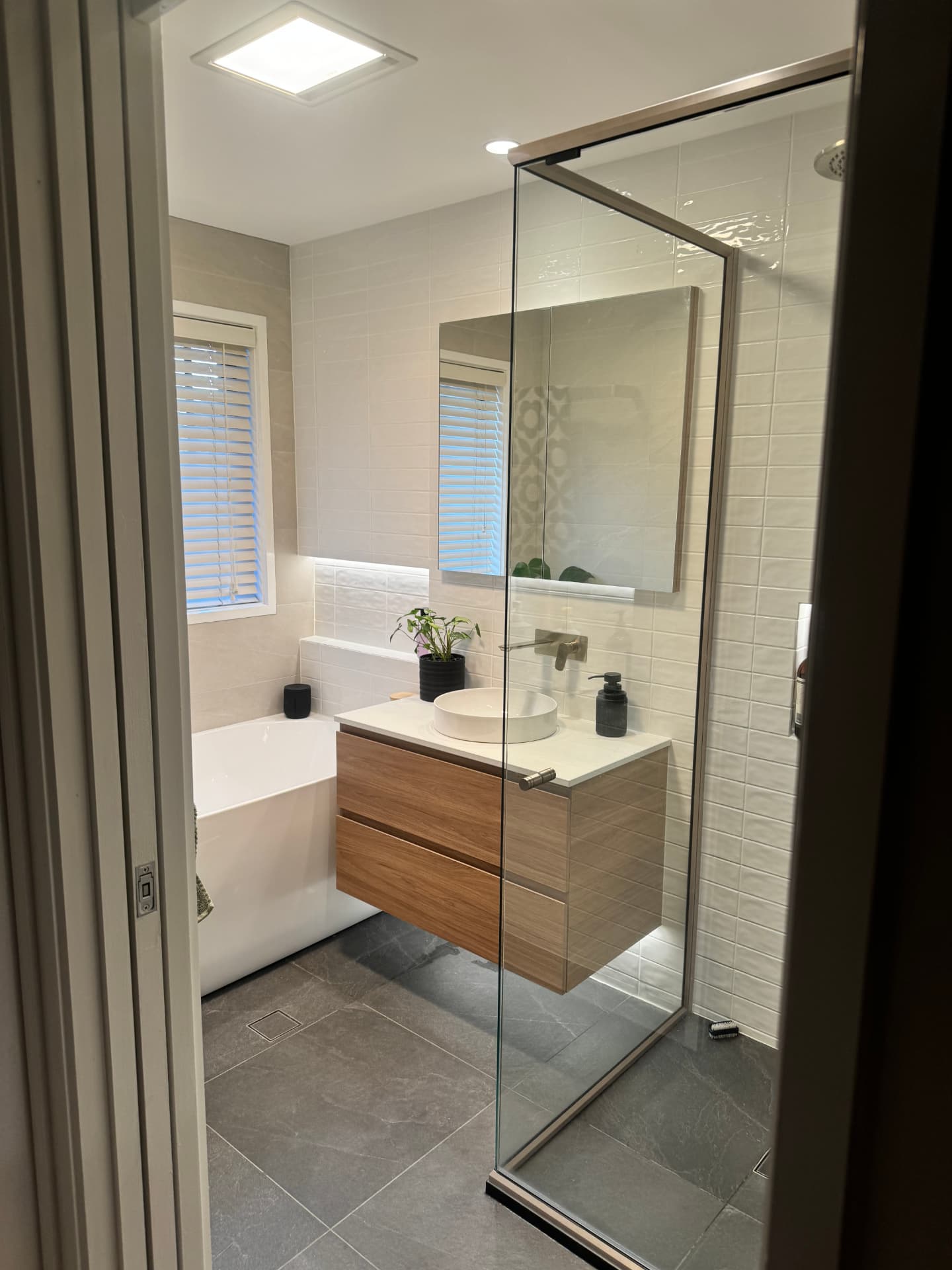 Renovated bathroom with backlit mirror cabinet, timber vanity and heat-lamp exhaust fan wired by MTK Electrics & Air in Canberra