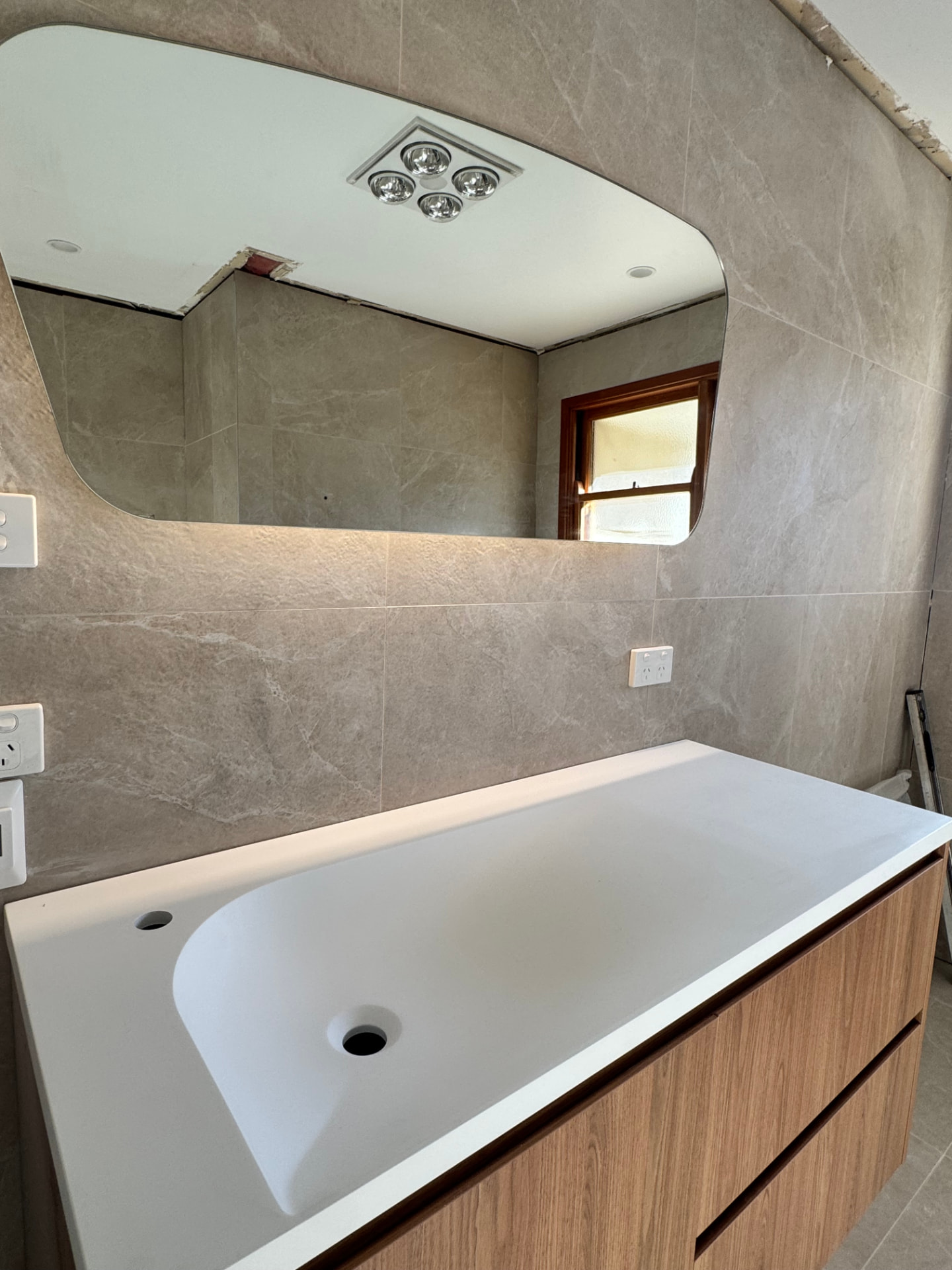 Tiled bathroom renovation with backlit mirror, vanity and heat-lamp exhaust fan wired by MTK Electrics & Air