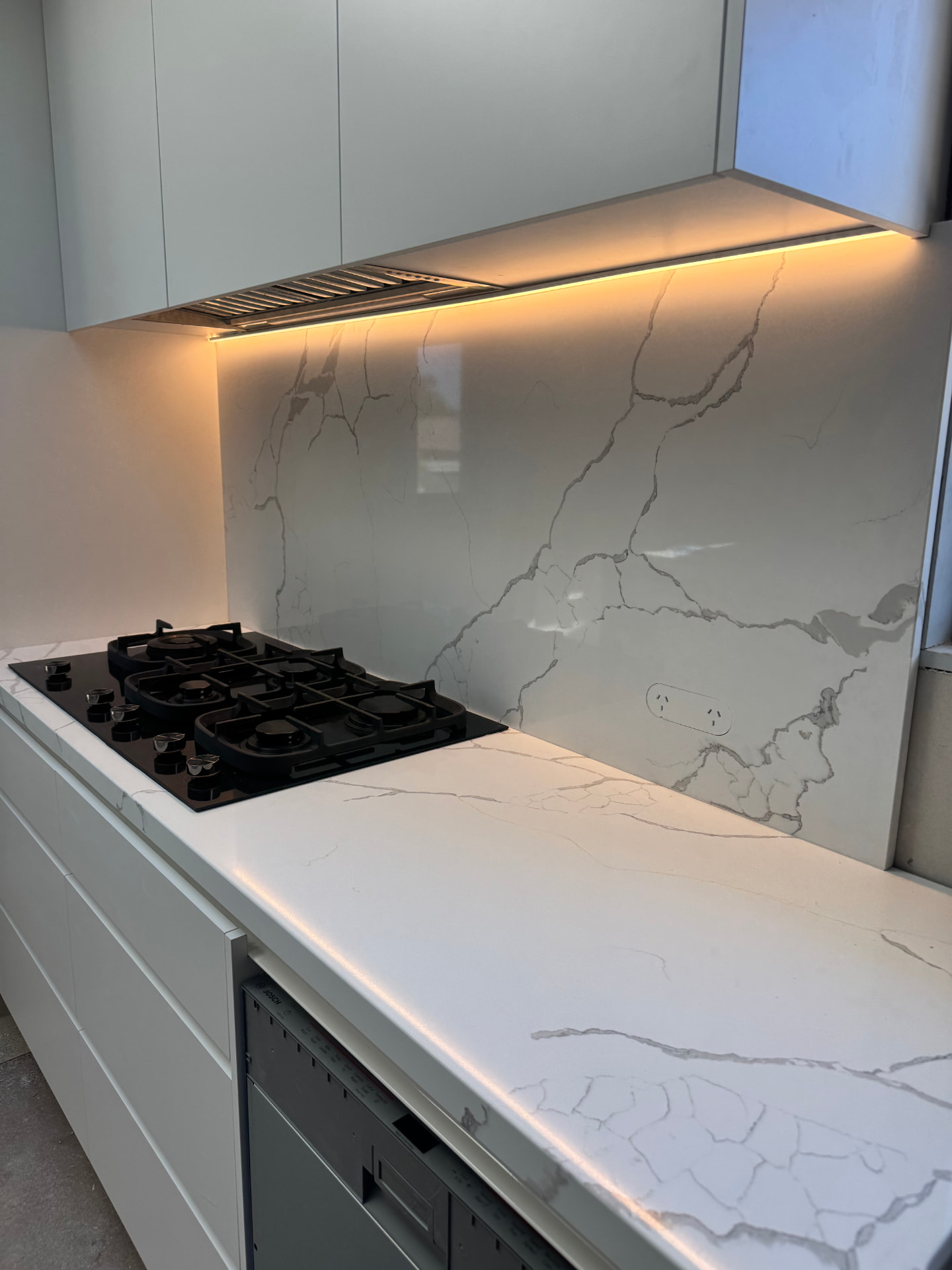 Kitchen with warm LED strip lighting under the rangehood and marble splashback installed by MTK Electrics & Air in Canberra